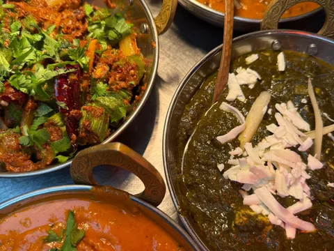 Karahis of curry, saag and chana served together at Midnight Temple