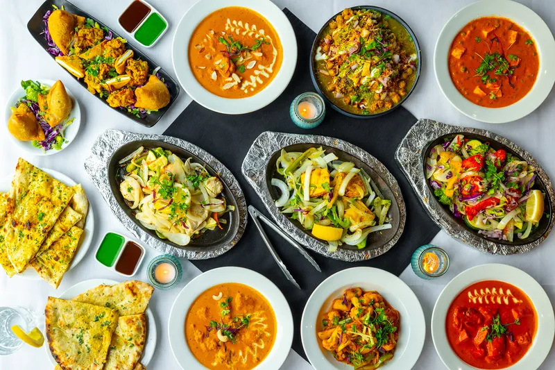 Overhead spread of curries, tandoori dishes and breads at Tandoori Flame