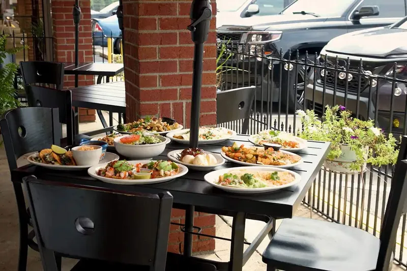 Patio table set with several entrees at Somos Familia