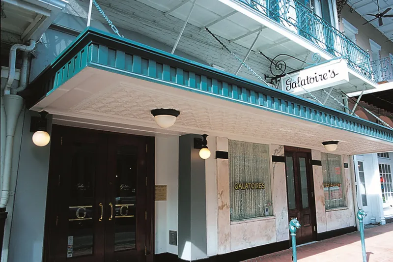 Exterior storefront of Galatoire's on Bourbon Street with its hanging sign and gold-lettered windows