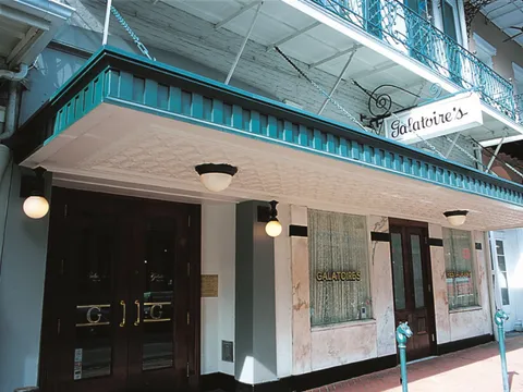 Exterior storefront of Galatoire's on Bourbon Street with its hanging sign and gold-lettered windows