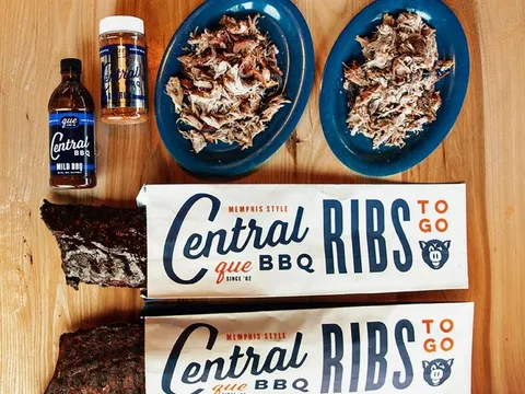 Central BBQ Memphis pulled pork on blue plates with smoked ribs, house BBQ sauce and dry rub, and branded Ribs To Go boxes