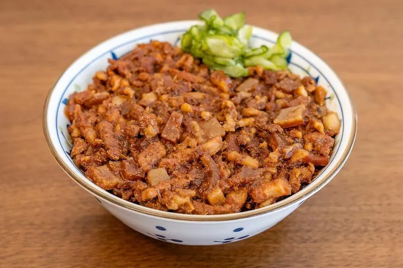 Bowl of Liu's Cafe braised pork belly rice with pickled cucumber