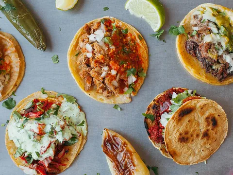 Overhead spread of tacos, salsas and grilled onions at Tacos El Gordo