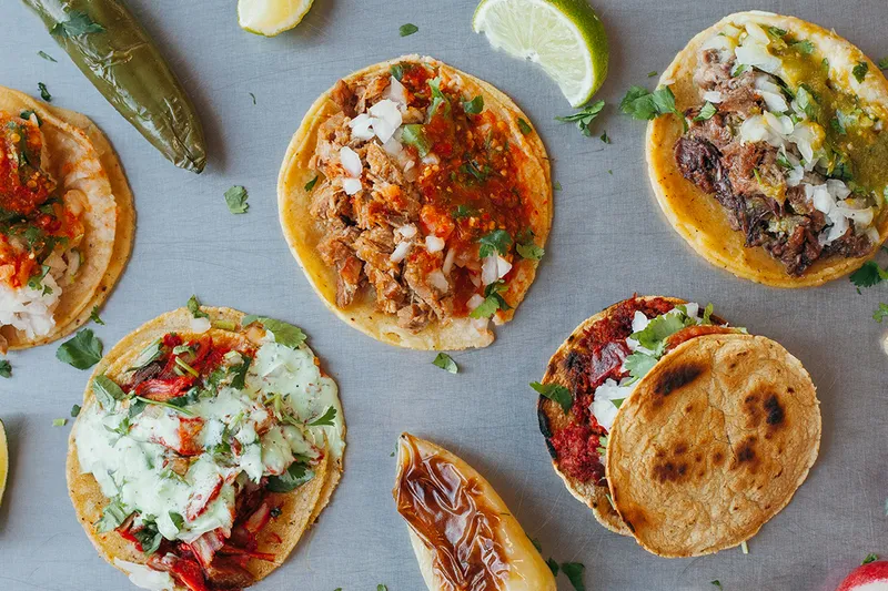 Overhead spread of tacos, salsas and grilled onions at Tacos El Gordo