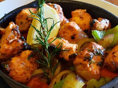 Sizzling chicken tikka with peppers and onions served in a cast-iron skillet at Marigold Maison in Phoenix