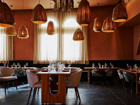 Dining room at Ikara, with terracotta walls, woven pendant lights and set tables
