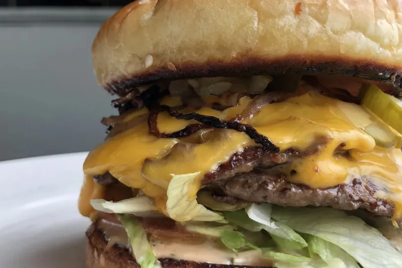 Close-up of a bacon cheeseburger with lettuce and pickles at Comet Cafe