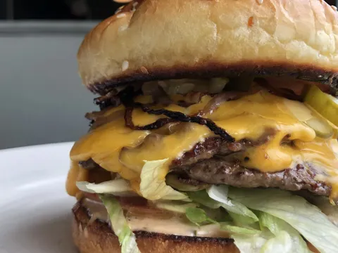 Close-up of a bacon cheeseburger with lettuce and pickles at Comet Cafe