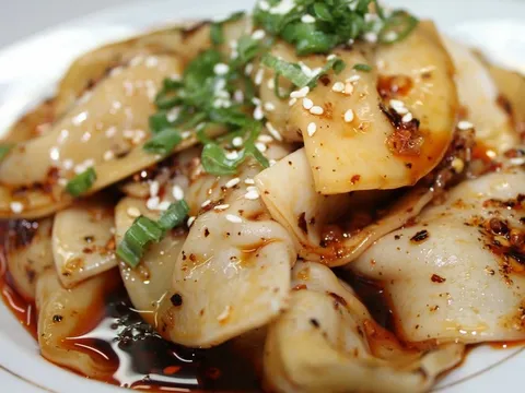 Plate of pork Zhong-style dumplings in chili oil topped with scallions and sesame seeds at Gu's Dumplings