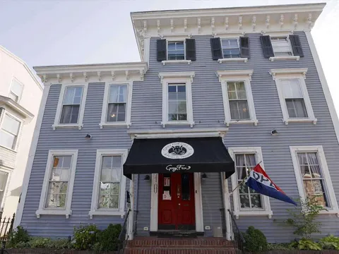 Grey clapboard building with a black awning over the entrance to Grey Fox Grille in downtown Dover