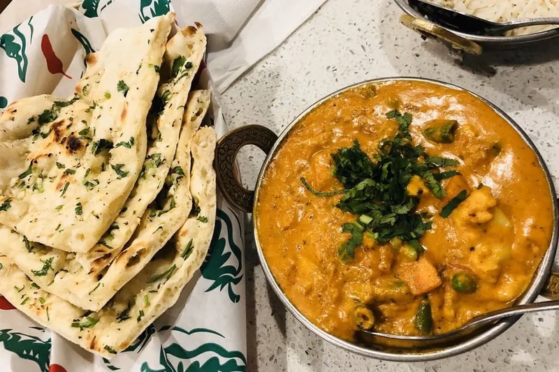 Garlic naan with a bowl of creamy vegetable korma and basmati rice at Bombay Delight