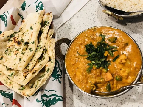 Garlic naan with a bowl of creamy vegetable korma and basmati rice at Bombay Delight