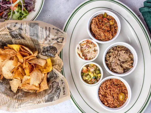 Plantain chips in newspaper wrap beside small bowls of Cuban sides at Santiago's