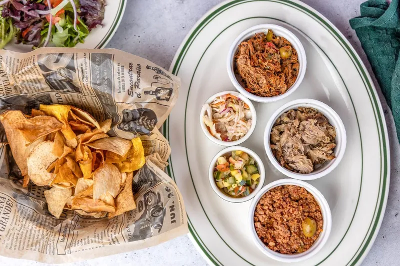Plantain chips in newspaper wrap beside small bowls of Cuban sides at Santiago's