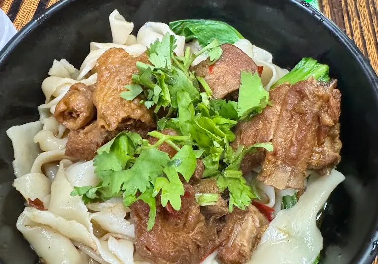 Bowl of hand-ripped noodles with braised meat at Spicy Village