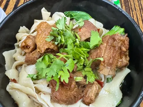 Bowl of hand-ripped noodles with braised meat at Spicy Village