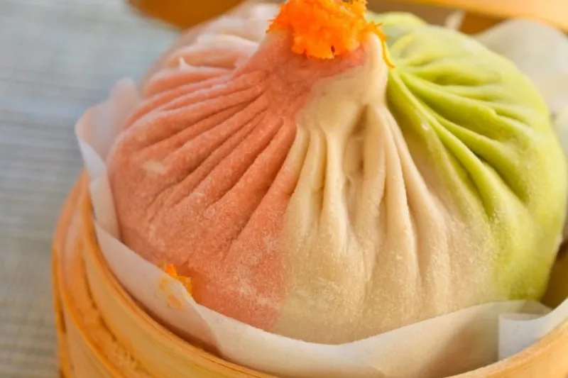 Colorful multi-flavored xiao long bao soup dumpling in a bamboo steamer at Shanghai You Garden