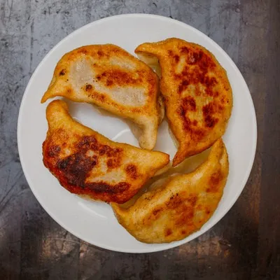Plate of pan-fried pork pot stickers browned on top at Shandong