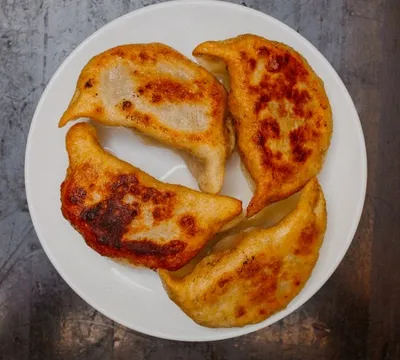 Plate of pan-fried pork pot stickers browned on top at Shandong