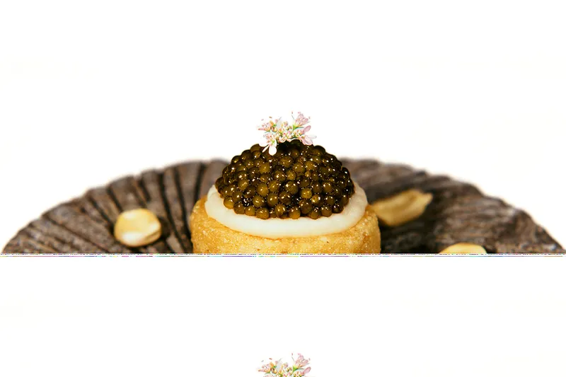 Small masa tart topped with caviar and a flower at Californios