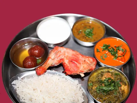 An Indian thali at India Palace in Memphis with tandoori chicken, dal, butter chicken, saag, basmati rice, raita and gulab jamun on a steel platter