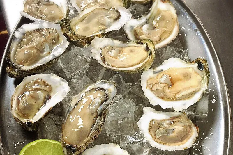 A metal platter of fresh shucked oysters on ice with lime wedges at Jarocho Pescados y Mariscos in Kansas City, Kansas