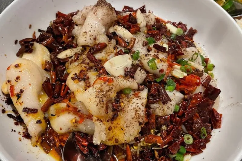 Sichuan boiled fish fillet with Szechuan peppercorns and dried chilies in a white bowl at Masterpiece