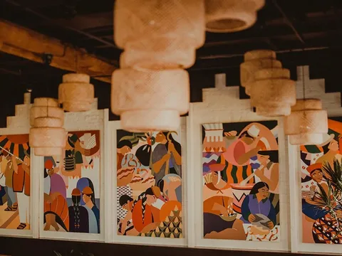 Andina's dining room in Portland with colorful painted murals of Andean scenes beneath woven pendant lamps