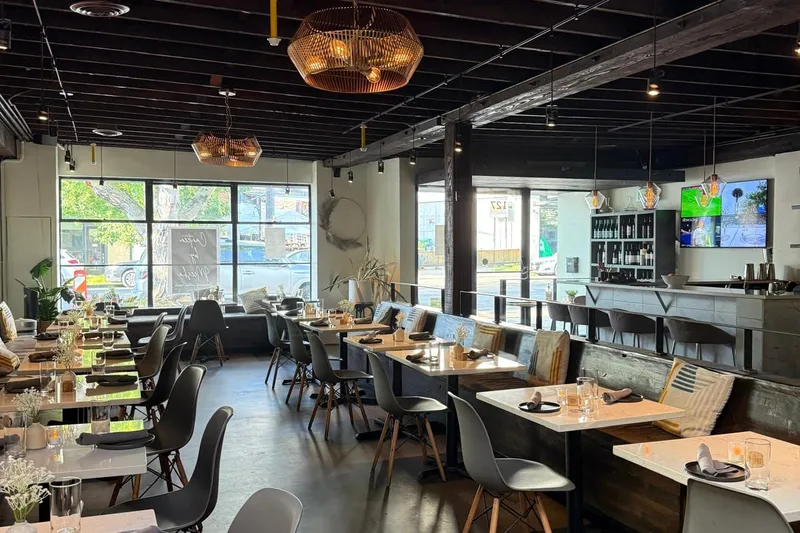 Dining room at Meesha, with tables on a concrete floor, a bar at the back and windows onto the street
