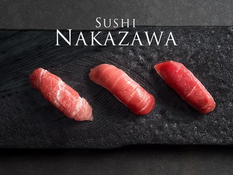 Three pieces of tuna nigiri (otoro, chutoro and akami) on a black slate plate, from the Sushi Nakazawa website