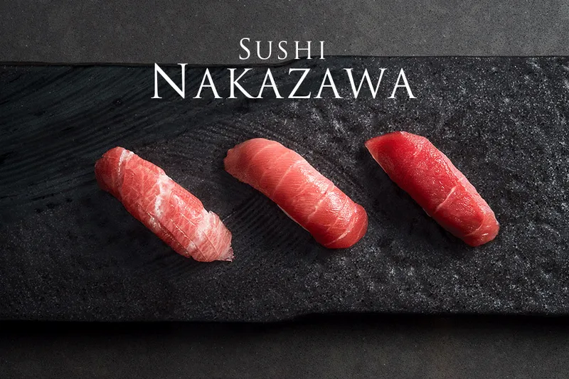 Three pieces of tuna nigiri (otoro, chutoro and akami) on a black slate plate, from the Sushi Nakazawa website