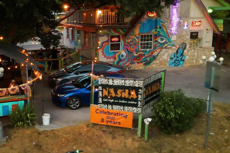 Mural-covered exterior and lit patio of Nasha on East 7th Street in Austin at dusk
