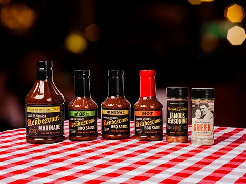 Bottles of Rendezvous barbecue sauce and seasoning lined up on a checkered tablecloth