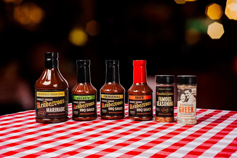 Bottles of Rendezvous barbecue sauce and seasoning lined up on a checkered tablecloth