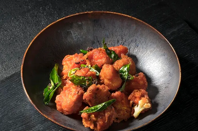Cauliflower Bezule with curry leaves in a dark bowl at Rasika