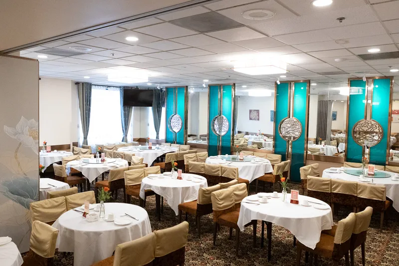 Interior banquet dining room at Peony Seafood Restaurant in Oakland, with round tables set with white linens, lazy Susans, and teal-and-gold decorative screens