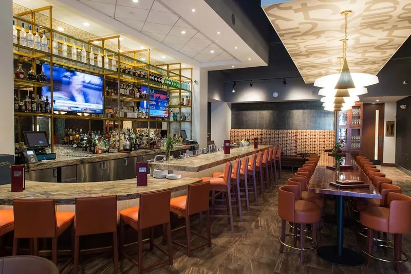 Bar and dining room at Kiran's, with a long bar, high stools and pendant lighting