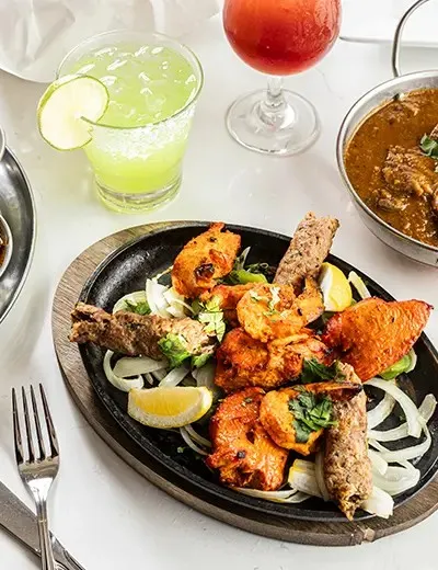 Sizzling tandoori mixed grill platter of kebabs and tikka with drinks and curry at Roti Grill