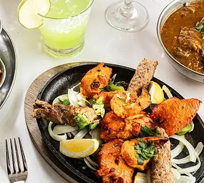 Sizzling tandoori mixed grill platter of kebabs and tikka with drinks and curry at Roti Grill