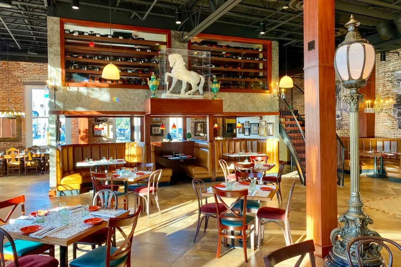 Dining room interior at Casa Santo Stefano in Ybor City, Tampa, with exposed brick, leather booths, a wine display and a white horse statue