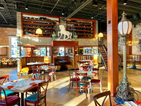 Dining room interior at Casa Santo Stefano in Ybor City, Tampa, with exposed brick, leather booths, a wine display and a white horse statue