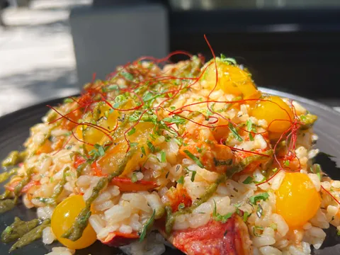 Lobster risotto with cherry tomatoes and herbs on a dark plate outside Mill's Tavern in Providence
