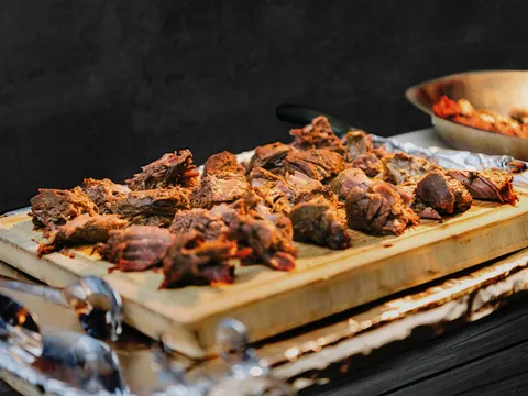 Wooden board of charcoal-barbecued meat from Anmol's catering spread