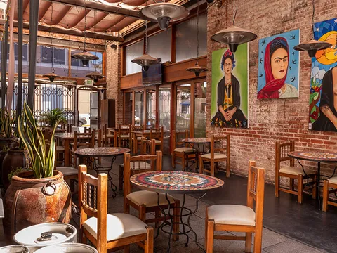 Mezcal's brick-walled dining room in downtown San Jose with mosaic-tile bistro tables, wooden chairs and painted portraits on the wall
