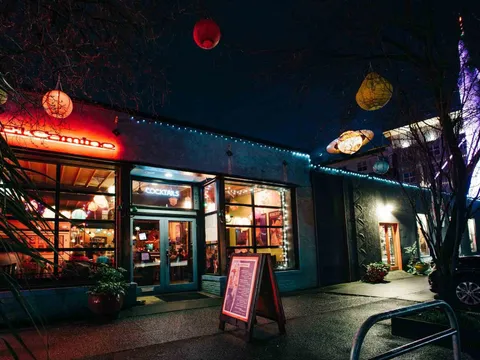 The El Camino storefront at night in Fremont, Seattle, with its glowing neon sign, strings of lights, paper lanterns and a lit "Cocktails" window at 607 N 35th Street