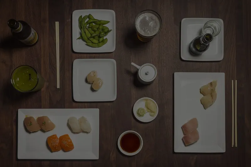 An overhead spread of Sugarfish nigiri, sashimi, edamame, beer and tea from the Trust Me menu at Sugarfish by Sushi Nozawa.
