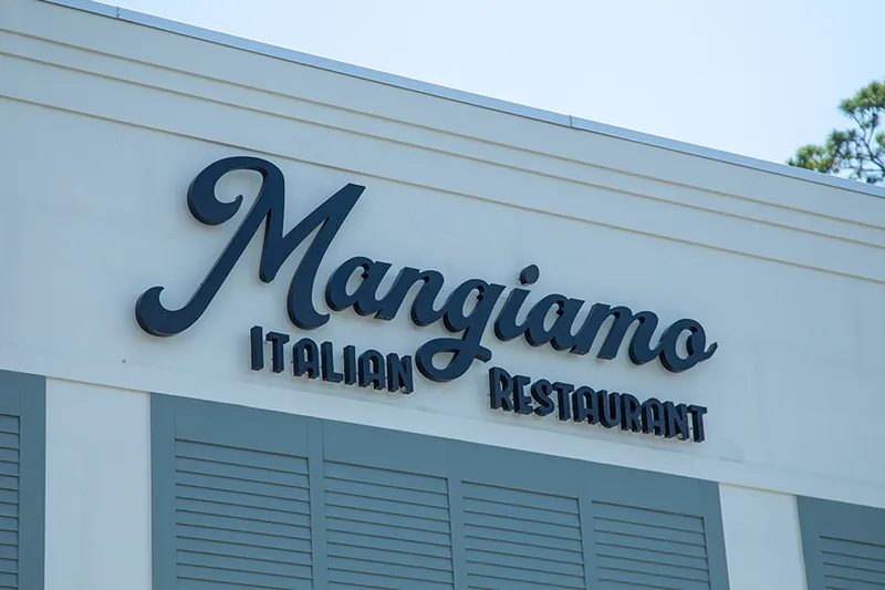 Script signage reading Mangiamo Italian Restaurant on a pale blue exterior wall