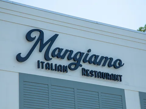 Script signage reading Mangiamo Italian Restaurant on a pale blue exterior wall