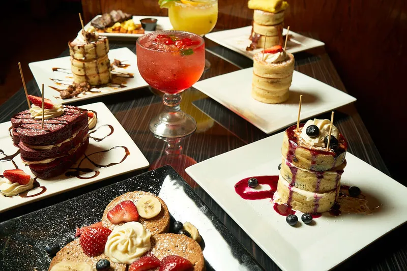 Brunch plates and a cocktail arranged on a dark table at Superhero Chefs